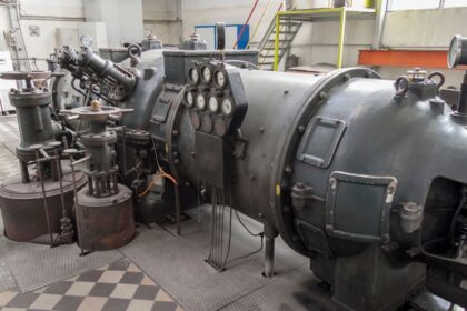 Equipamento industrial de grande porte com cilindro metálico, válvulas e painel de manômetros instalado em ambiente fabril para controle de pressão e processos técnicos.