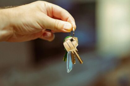 Mão segurando um molho de chaves com chaveiro, simbolizando entrega de imóvel alugado e início de contrato de locação.