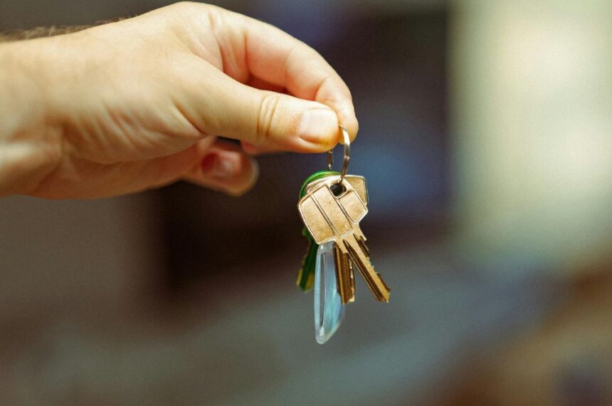 Mão segurando um molho de chaves com chaveiro, simbolizando entrega de imóvel alugado e início de contrato de locação.